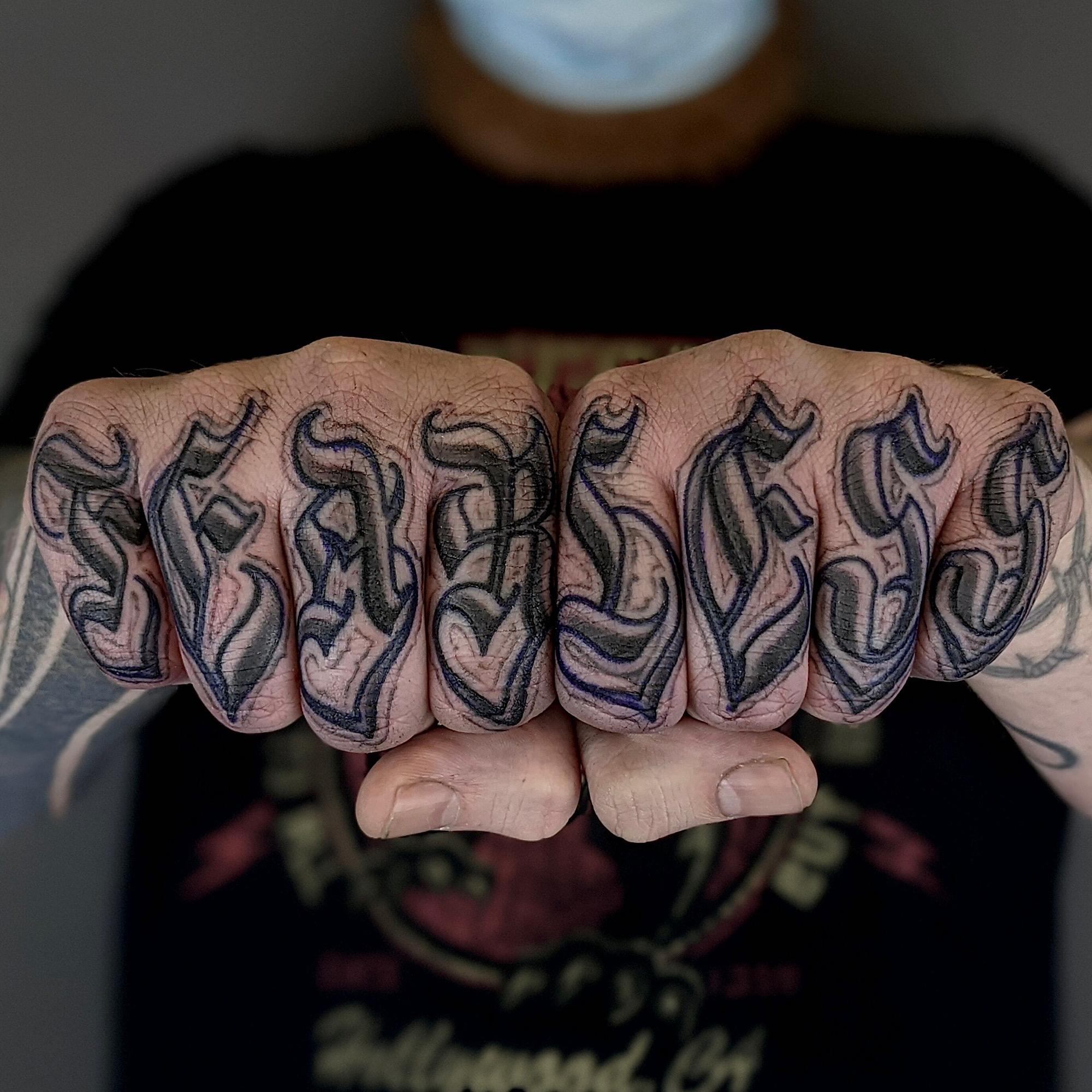 old english blackletter gothic style lettering across fingers love letters black and grey gray lettering hand tattoo by Ricks custom tattooing Ricardo Pedro at Nexus Collective