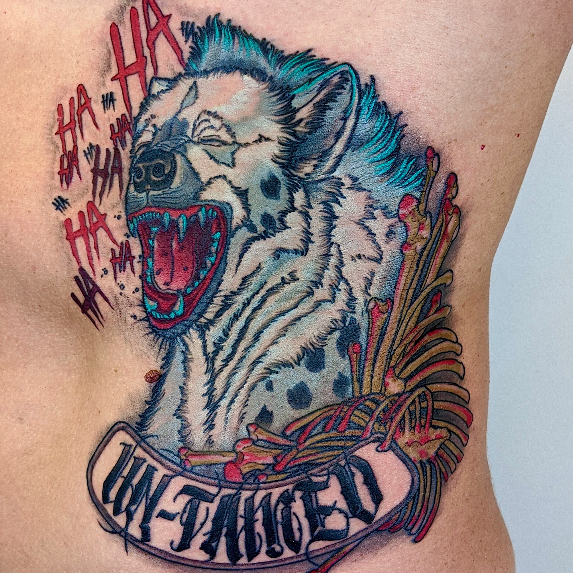 Laughing hyena with jokers hahaha neo traditional tattoo on a bed of bones with words untamed un-tamed by Ricks custom tattooing Ricardo Pedro at Nexus Collective